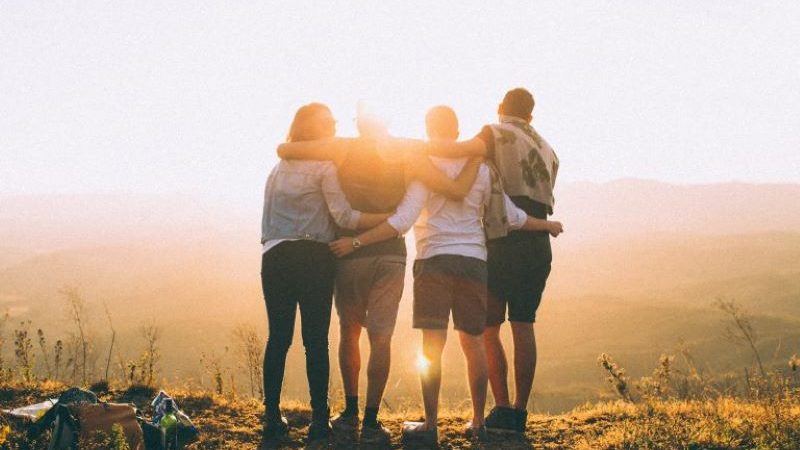 people with arms around each other face the sunset