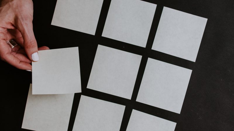 hand picks up a square paper from a grid