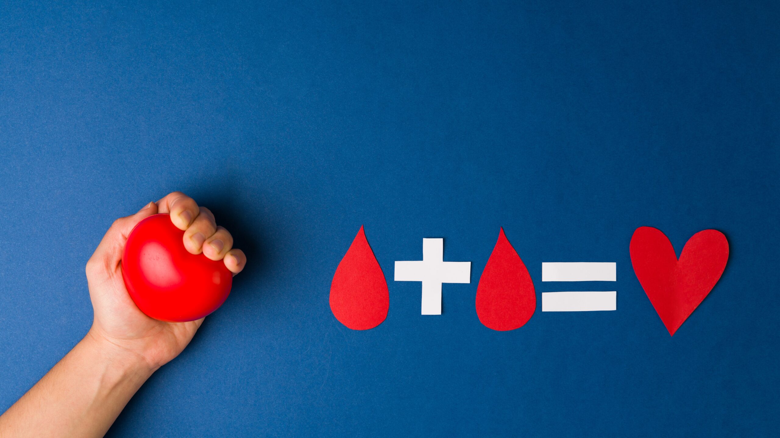 hand holding a heart shaped stress ball, next to a red blood droplet graphic on a blue background