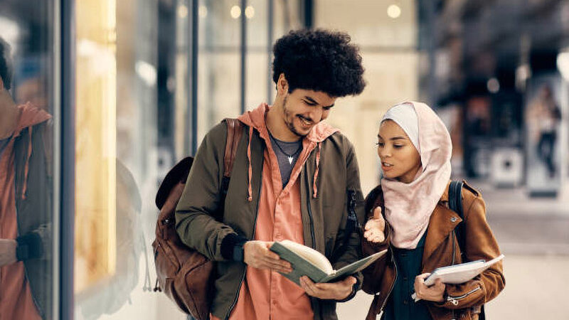 Happy Middle Eastern couple reading lecture notes after the class at the university.